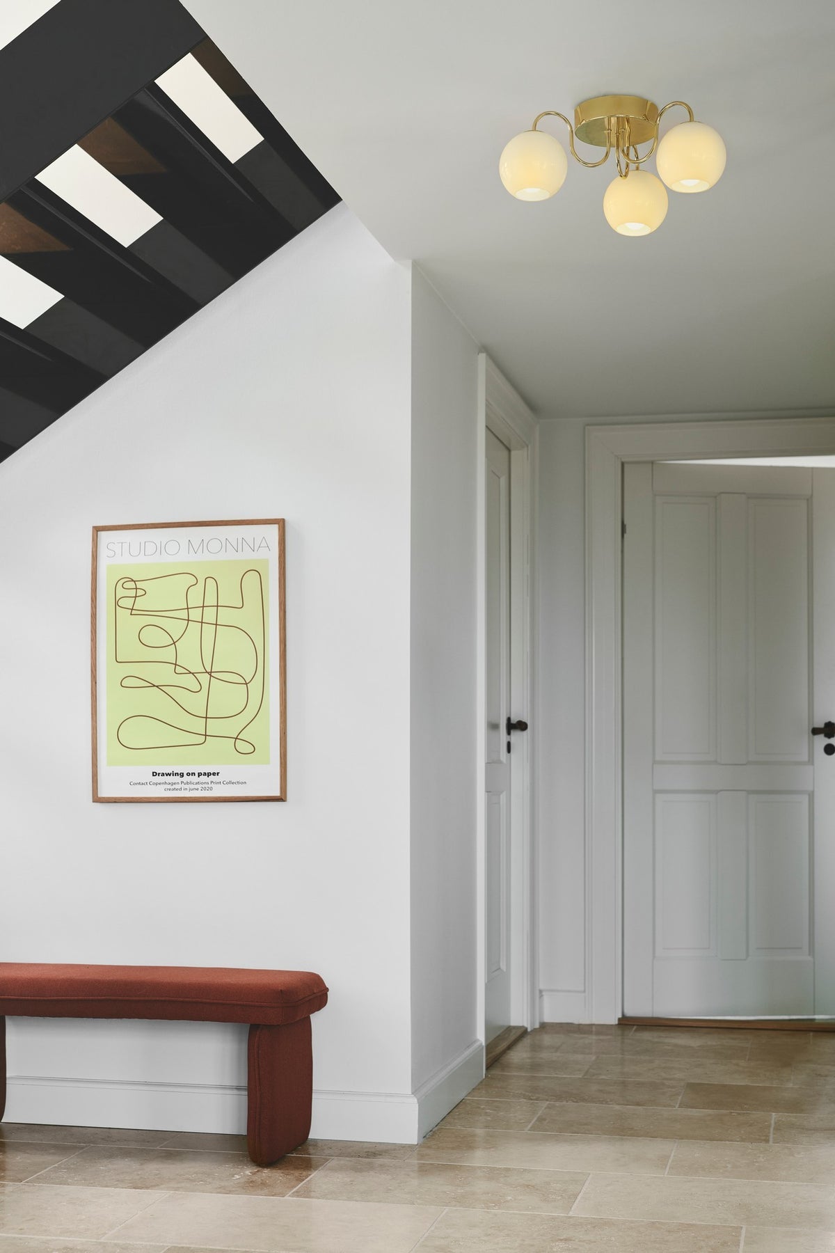 Même plafonnier allumé diffusant une lumière chaude dans l'entrée blanche.