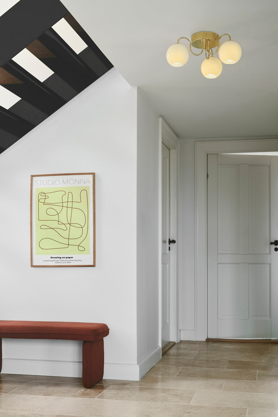 Même plafonnier allumé diffusant une lumière chaude dans l'entrée blanche.