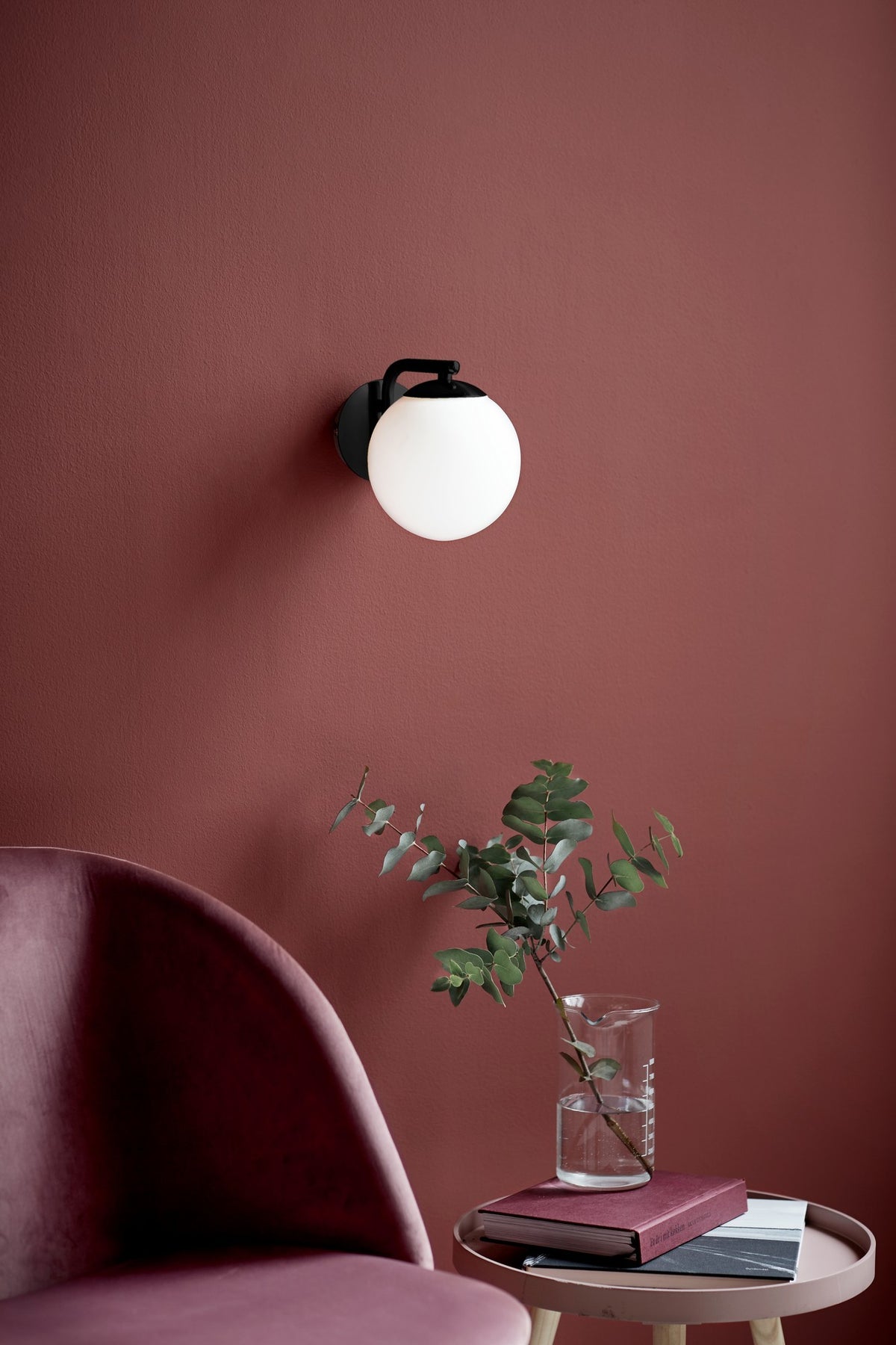 Mise en ambiance sur mur terracotta avec fauteuil et vase de feuillages