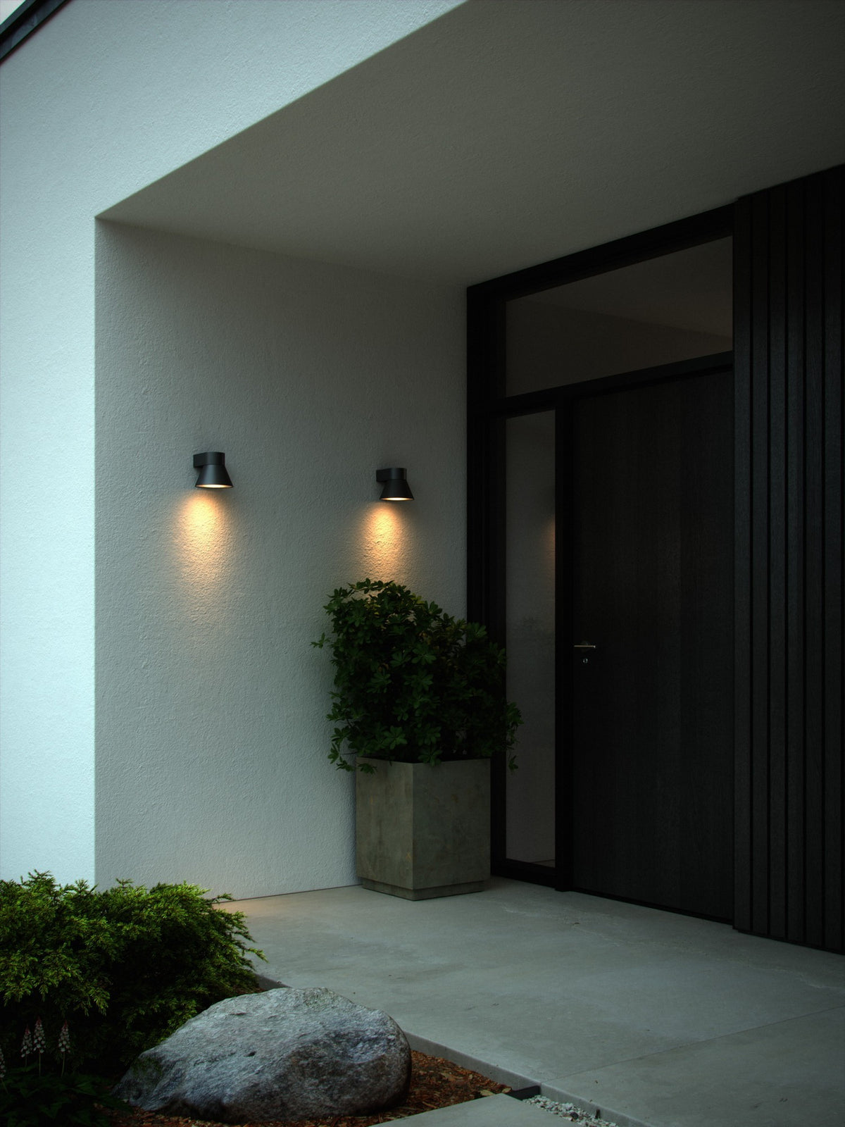 Mise en ambiance extérieure, deux appliques noires allumées sur mur blanc près porte.