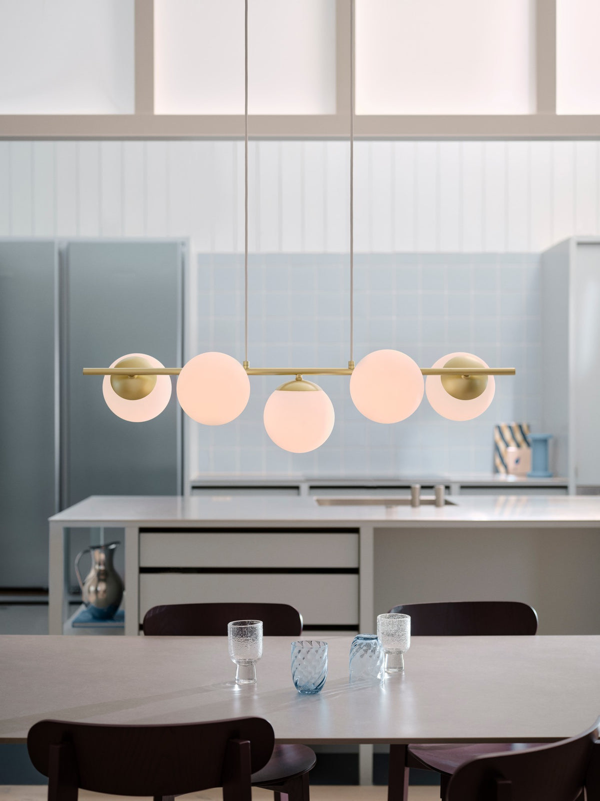 Mise en ambiance dans une cuisine moderne, suspension allumée au-dessus de la table