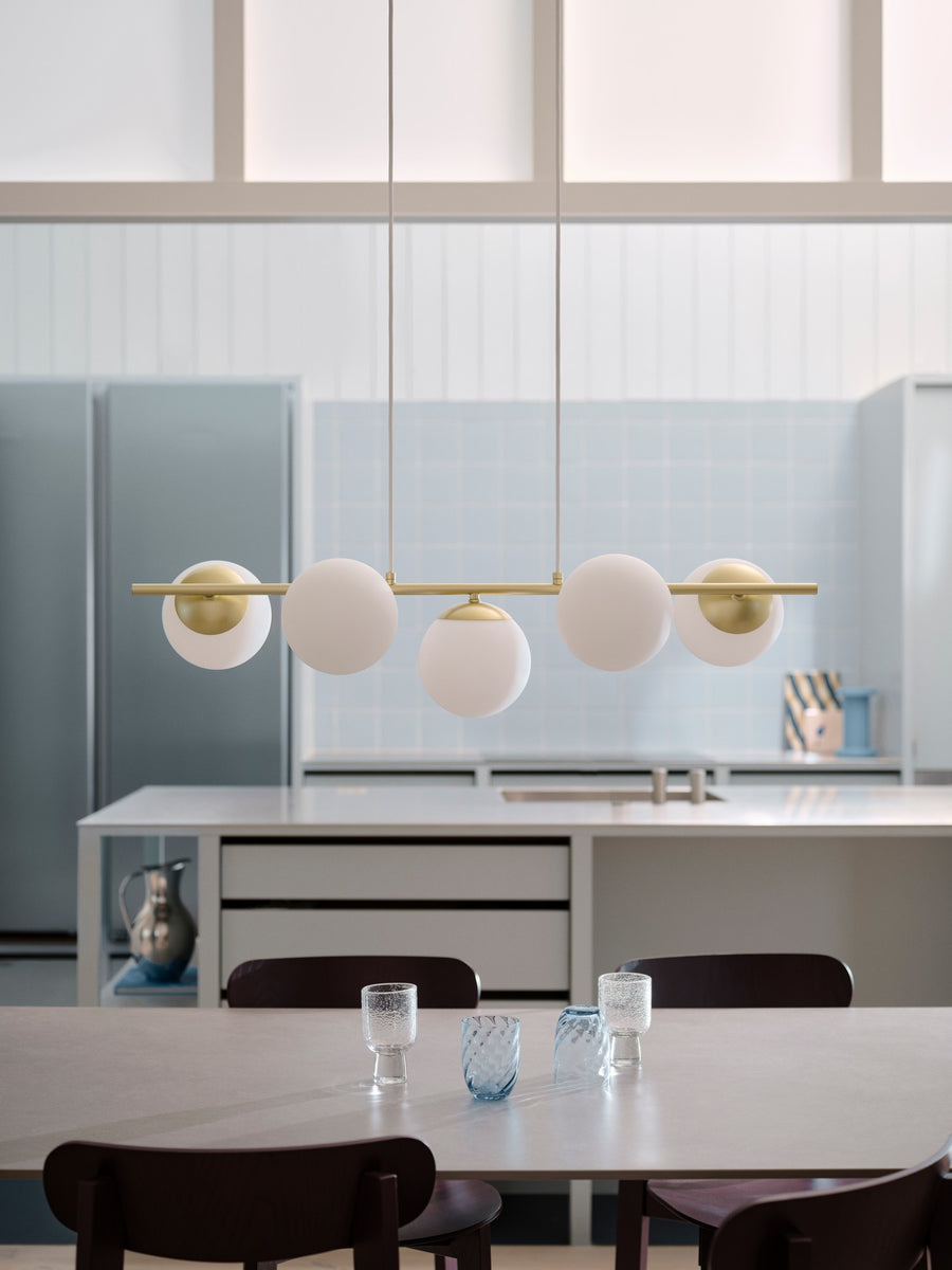 Ambiance cuisine claire, luminaire éteint suspendu devant les meubles blancs