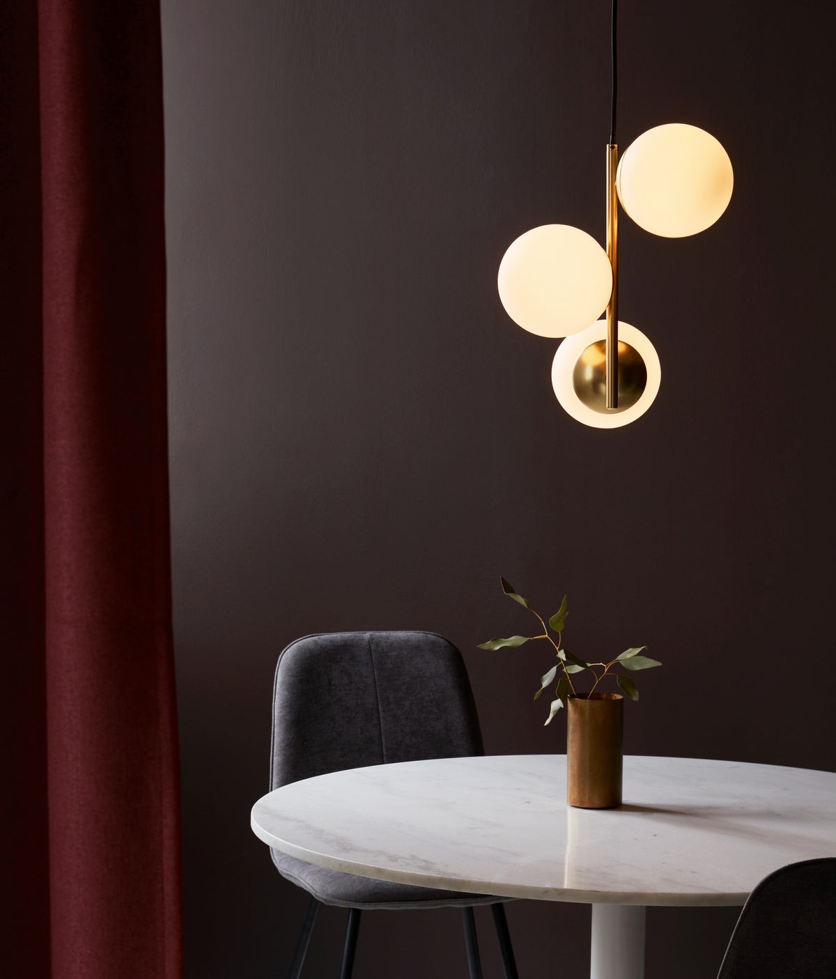 Mise en ambiance de la suspension allumée au-dessus d'une table ronde en marbre.