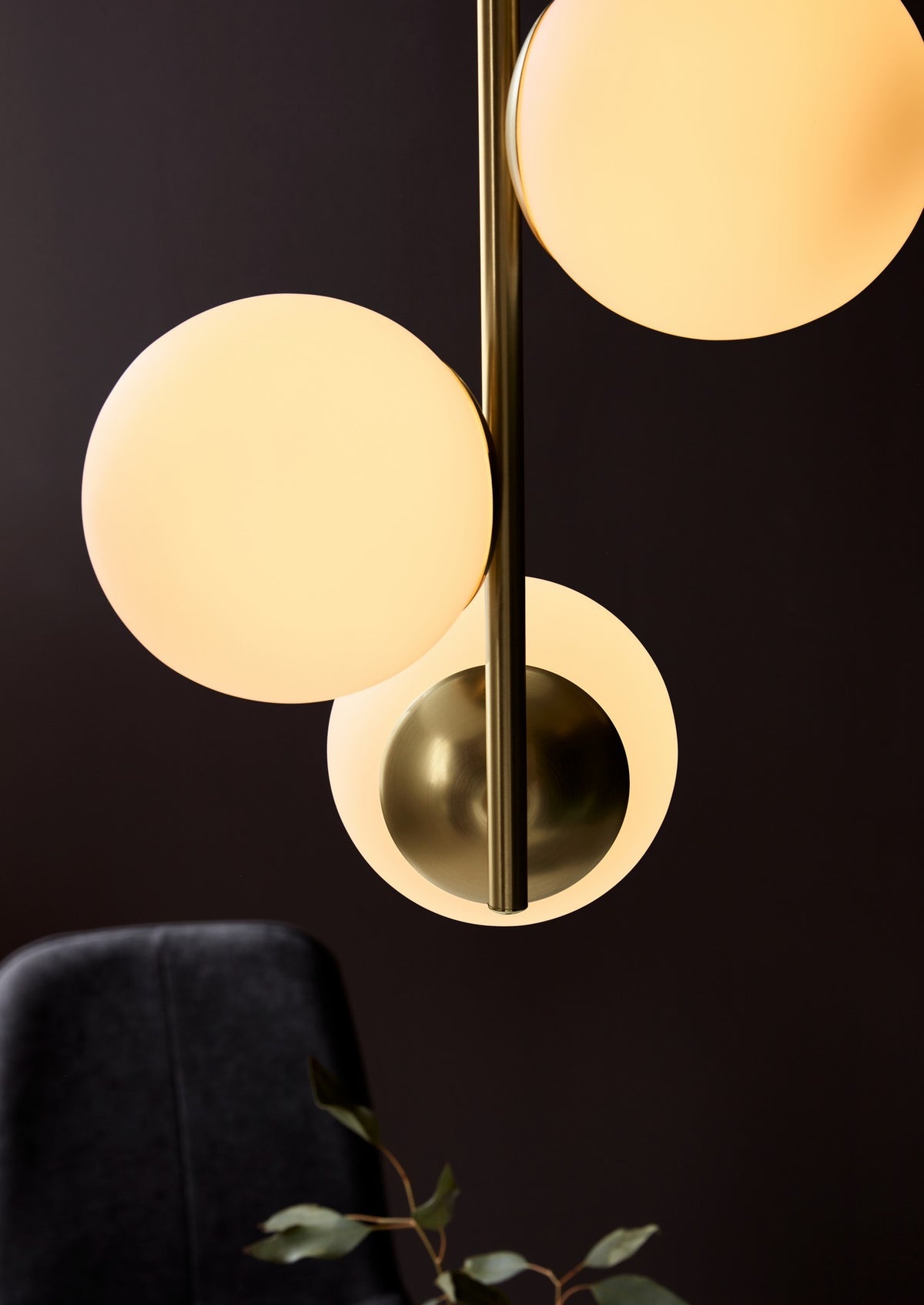 Détail rapproché des globes allumés, du laiton et du verre dépoli sur fond sombre.