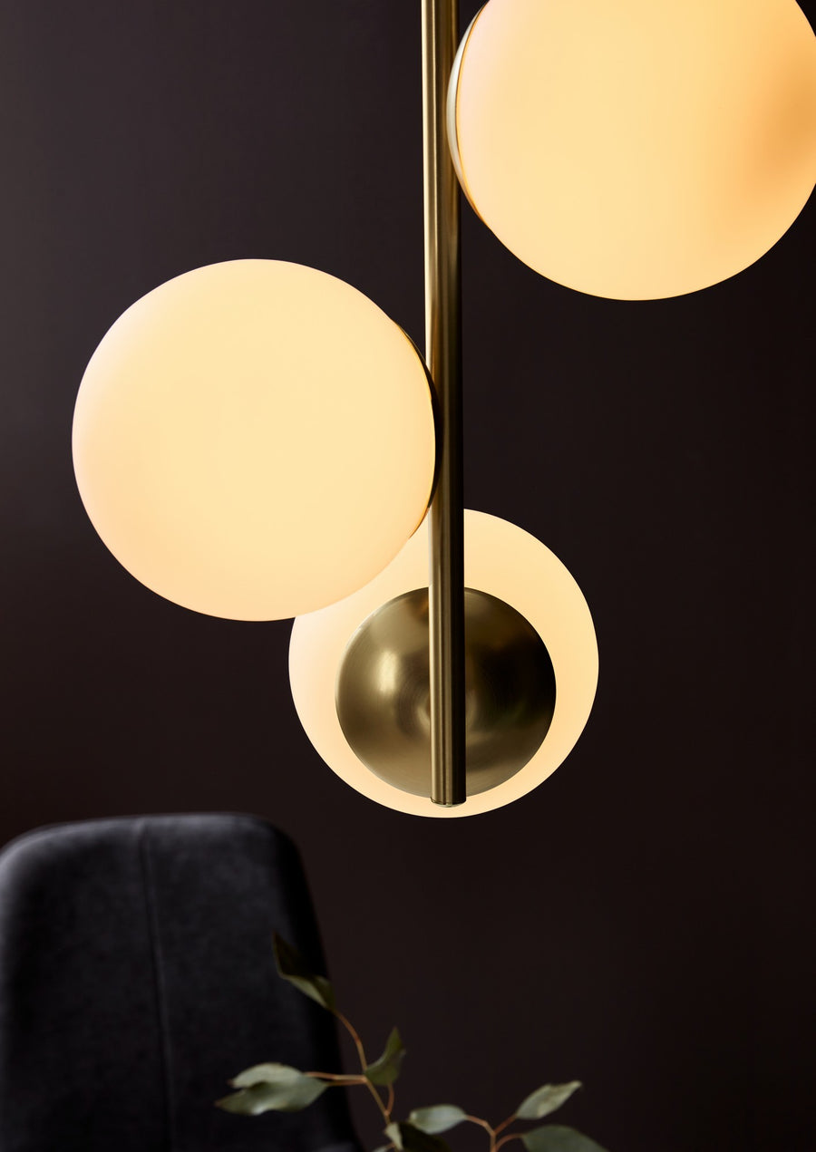 Détail rapproché des globes allumés, du laiton et du verre dépoli sur fond sombre.
