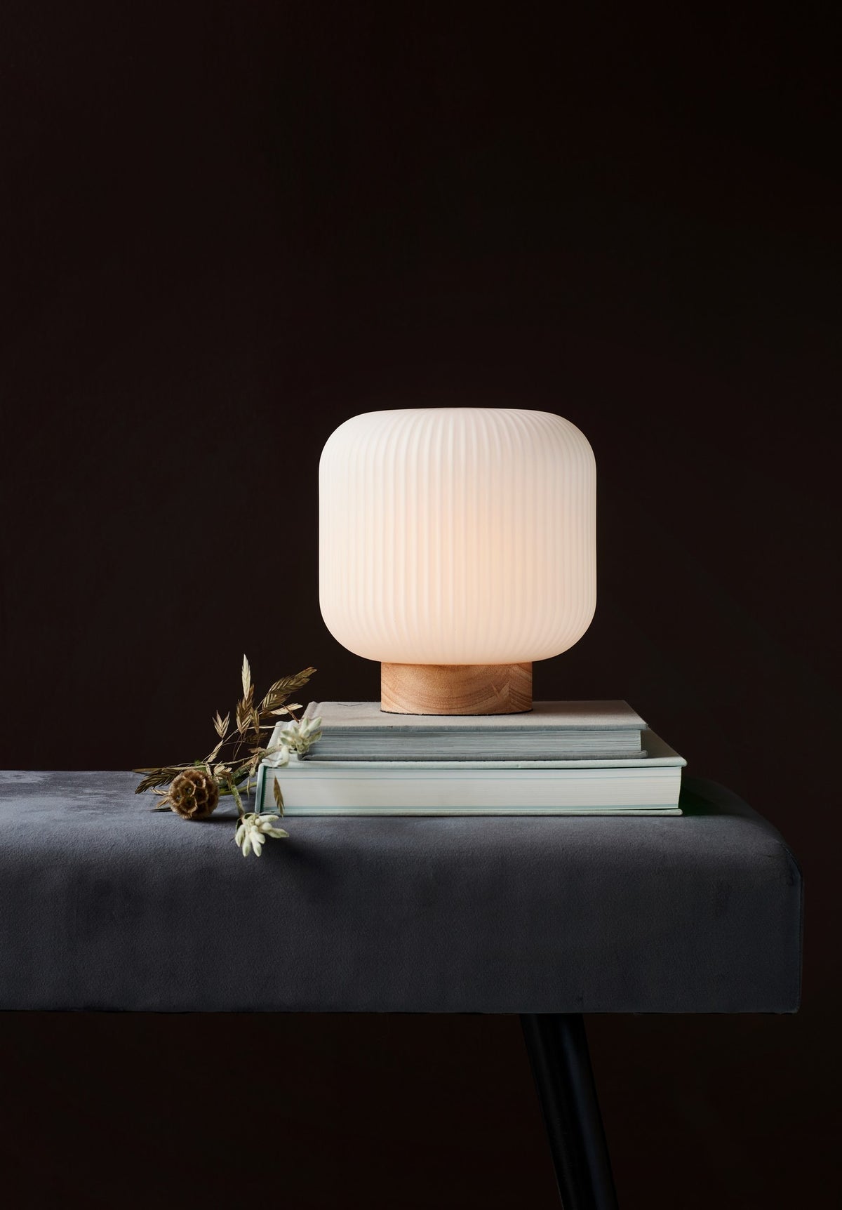 Mise en ambiance sombre, lampe allumée posée sur une pile de livres
