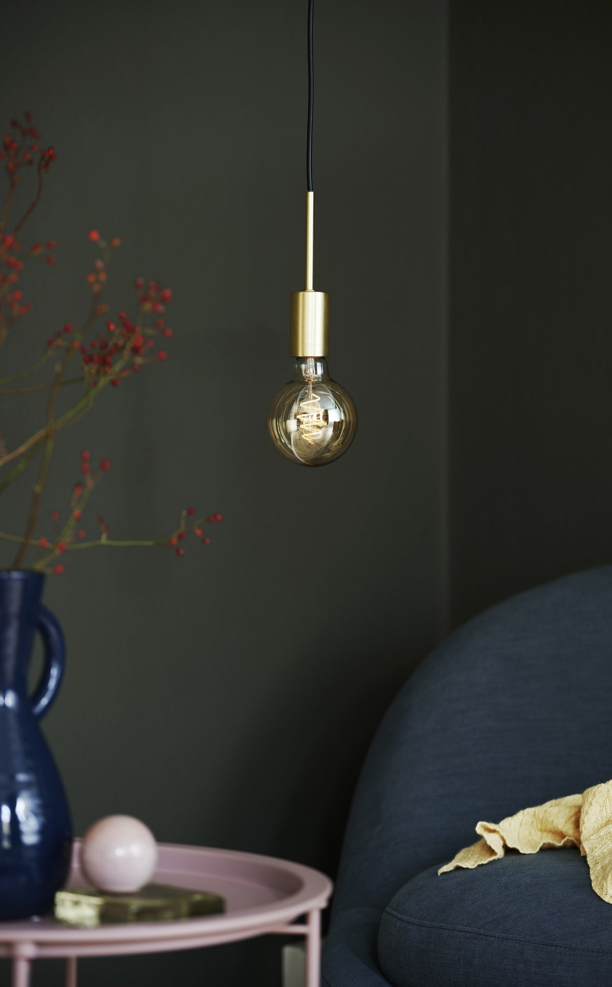Mise en ambiance dans un intérieur sombre, suspension allumée avec ampoule à filament.