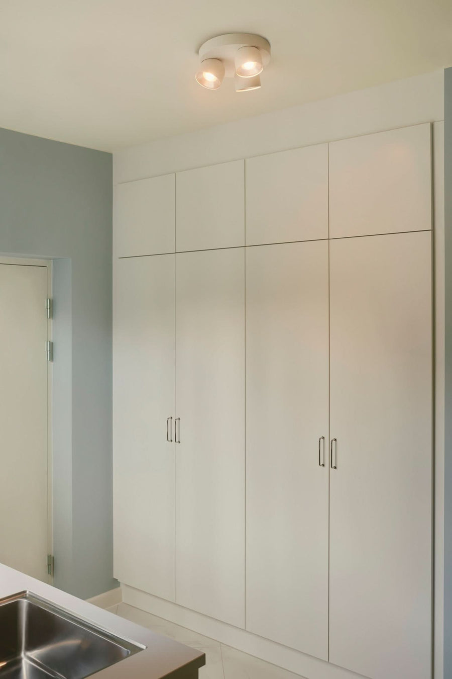 Mise en situation dans une pièce avec placards blancs, luminaire fixé au plafond