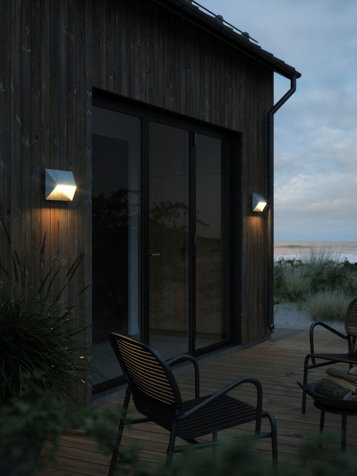 Mise en ambiance sur façade en bois, deux appliques allumées au crépuscule