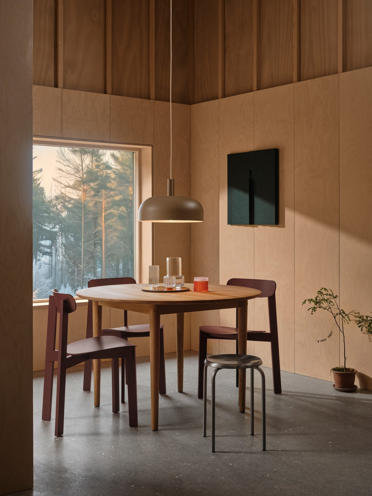 Mise en ambiance dans une salle à manger en bois, suspension allumée au-dessus de la table.