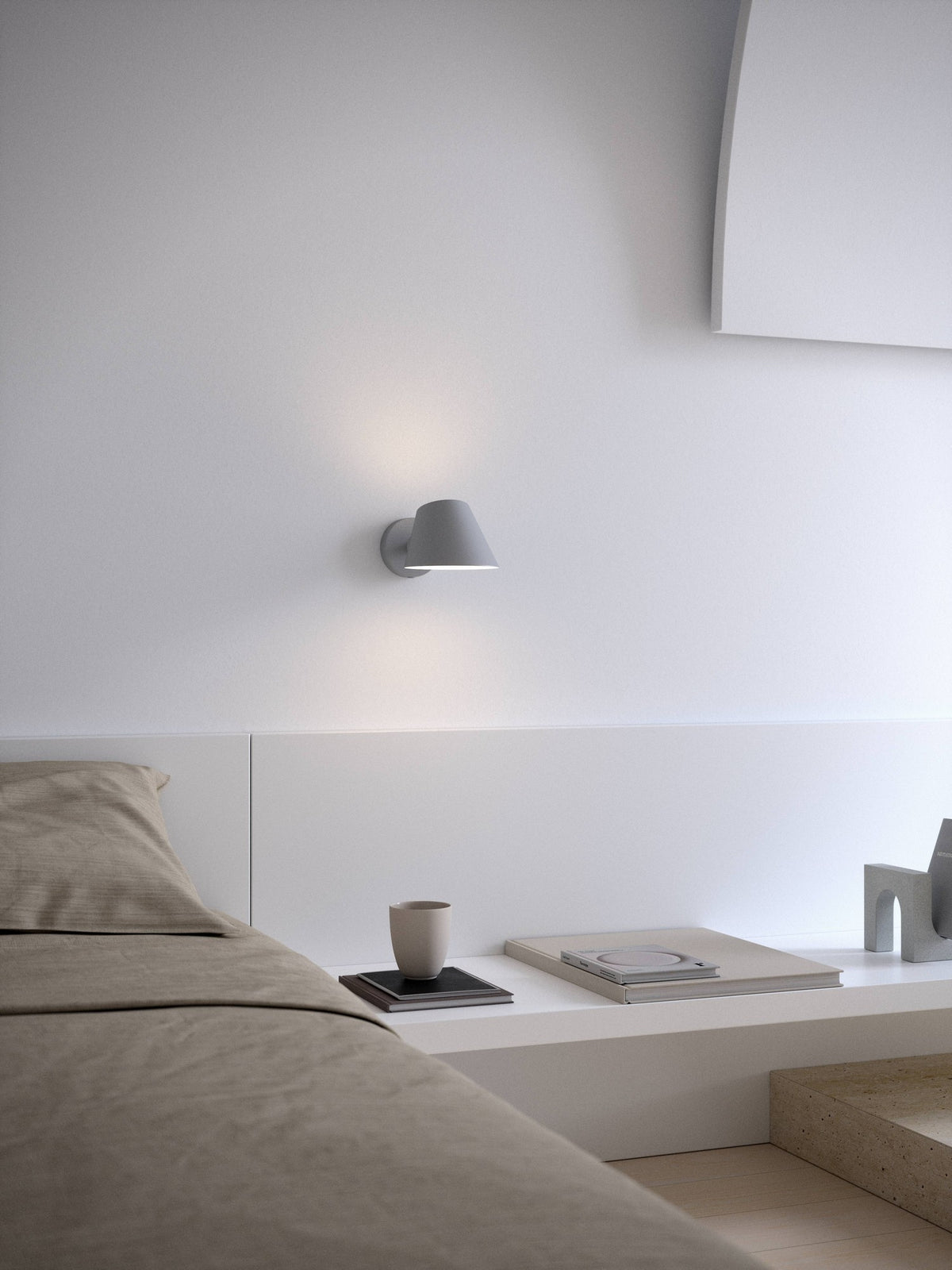 Mise en ambiance dans une chambre minimaliste, applique allumée au-dessus du lit