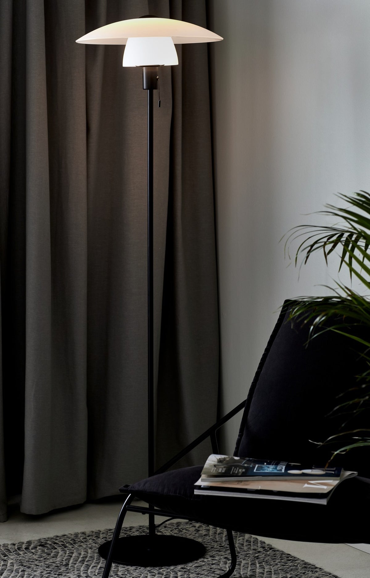 Mise en ambiance du lampadaire allumé près d'un fauteuil et de rideaux