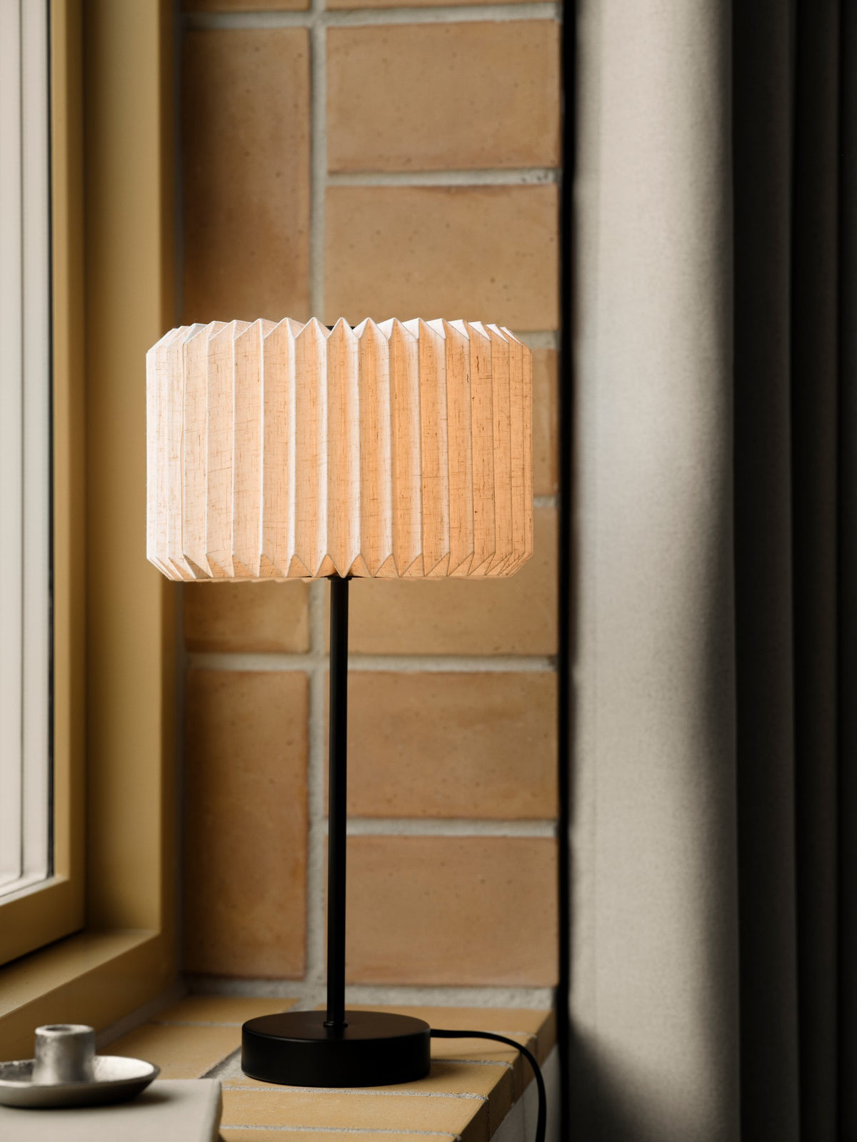 Mise en ambiance sur un rebord de fenêtre, abat-jour beige allumé