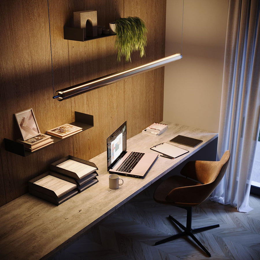 Long tube suspendu éclairant un bureau en bois avec ordinateur portable