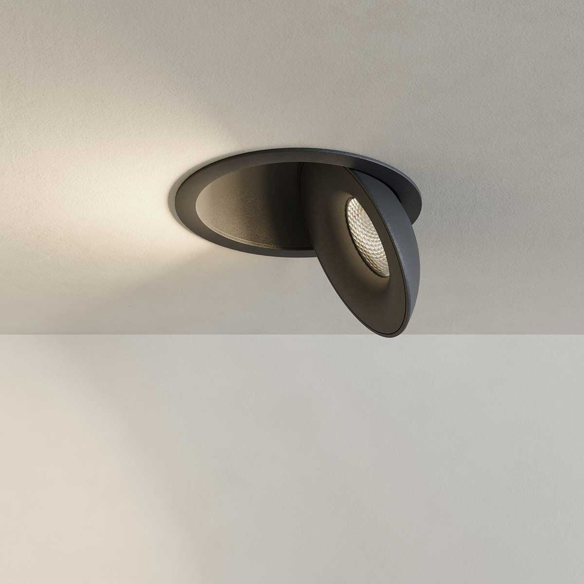 Spot noir orientable en gros plan, faisceau chaud projeté sur plafond crème