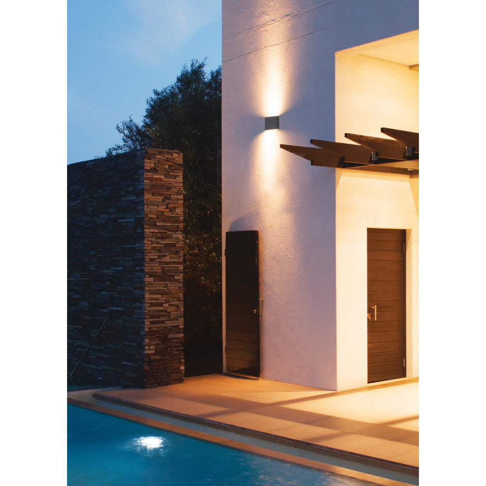 Mise en ambiance au bord d'une piscine, applique éclairant une façade blanche au crépuscule