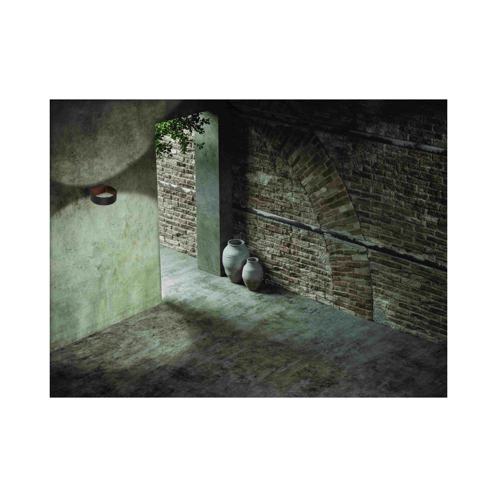 Ambiance nocturne dans une cour, applique murale éclairant un mur de briques.