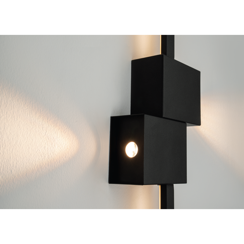 Détail rapproché de la finition noire mate et du halo lumineux sur le mur