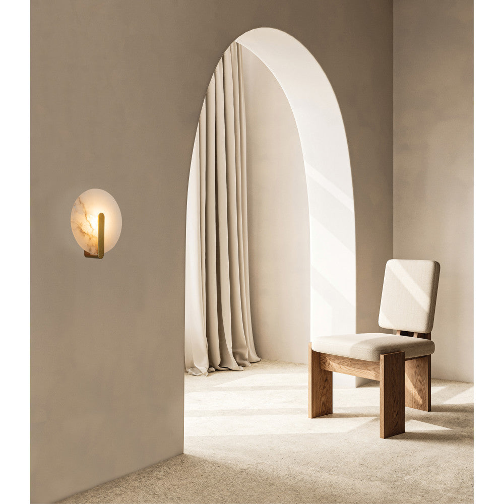 Mise en ambiance dans un intérieur beige, applique allumée près d'une arche.
