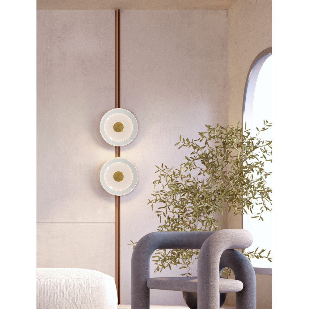 Mise en ambiance de deux appliques rondes superposées sur un mur clair avec plante verte