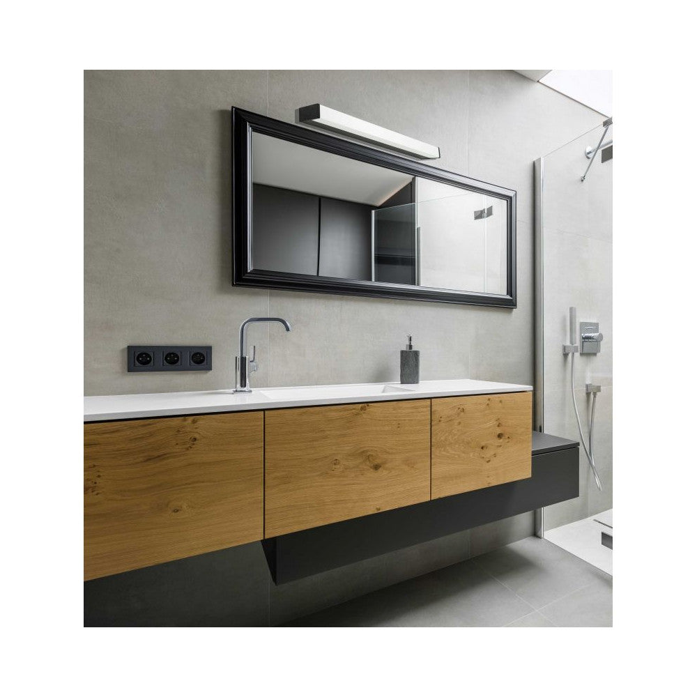 Applique murale allumée au-dessus d'un miroir noir dans une salle de bain bois