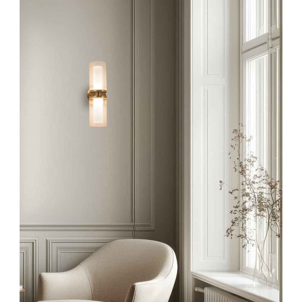 Vue d'ambiance dans un salon, applique dorée sur mur gris près d'une fenêtre et d'un fauteuil.