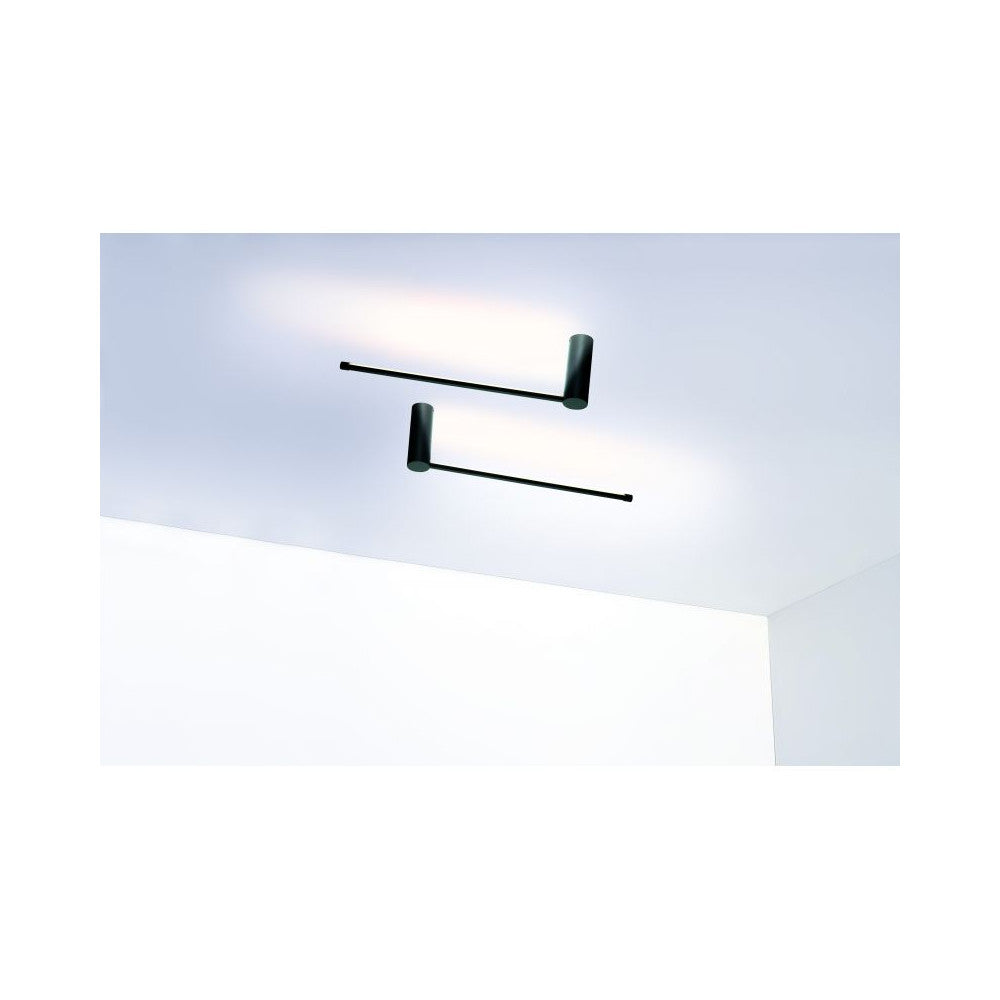 Deux luminaires noirs fixés au plafond avec bras linéaires éclairant vers le haut.