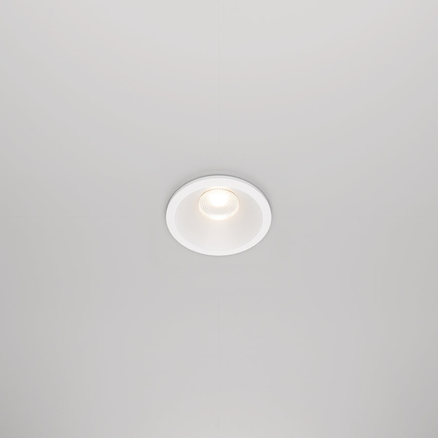 Spot encastré blanc rond allumé, installé au plafond en situation