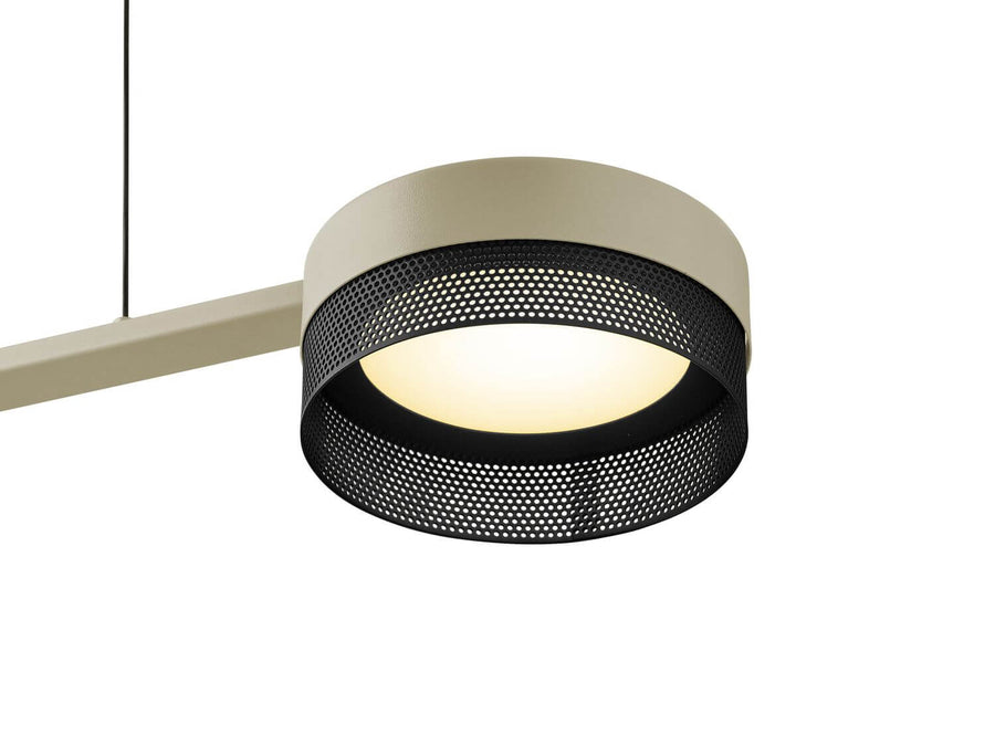 Gros plan sur un abat-jour cylindrique en maille perforée noire et diffuseur blanc allumé.