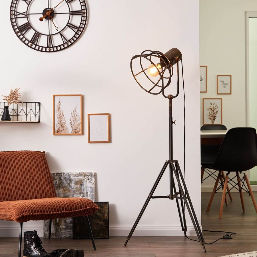 Lampadaire allumé devant mur blanc, près fauteuil orange et horloge murale
