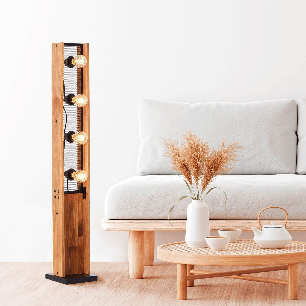 Lampadaire dans un salon, près d'un canapé blanc, table basse en bois et pampas.