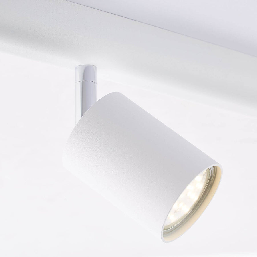Gros plan sur un spot blanc orientable et sa fixation chromée