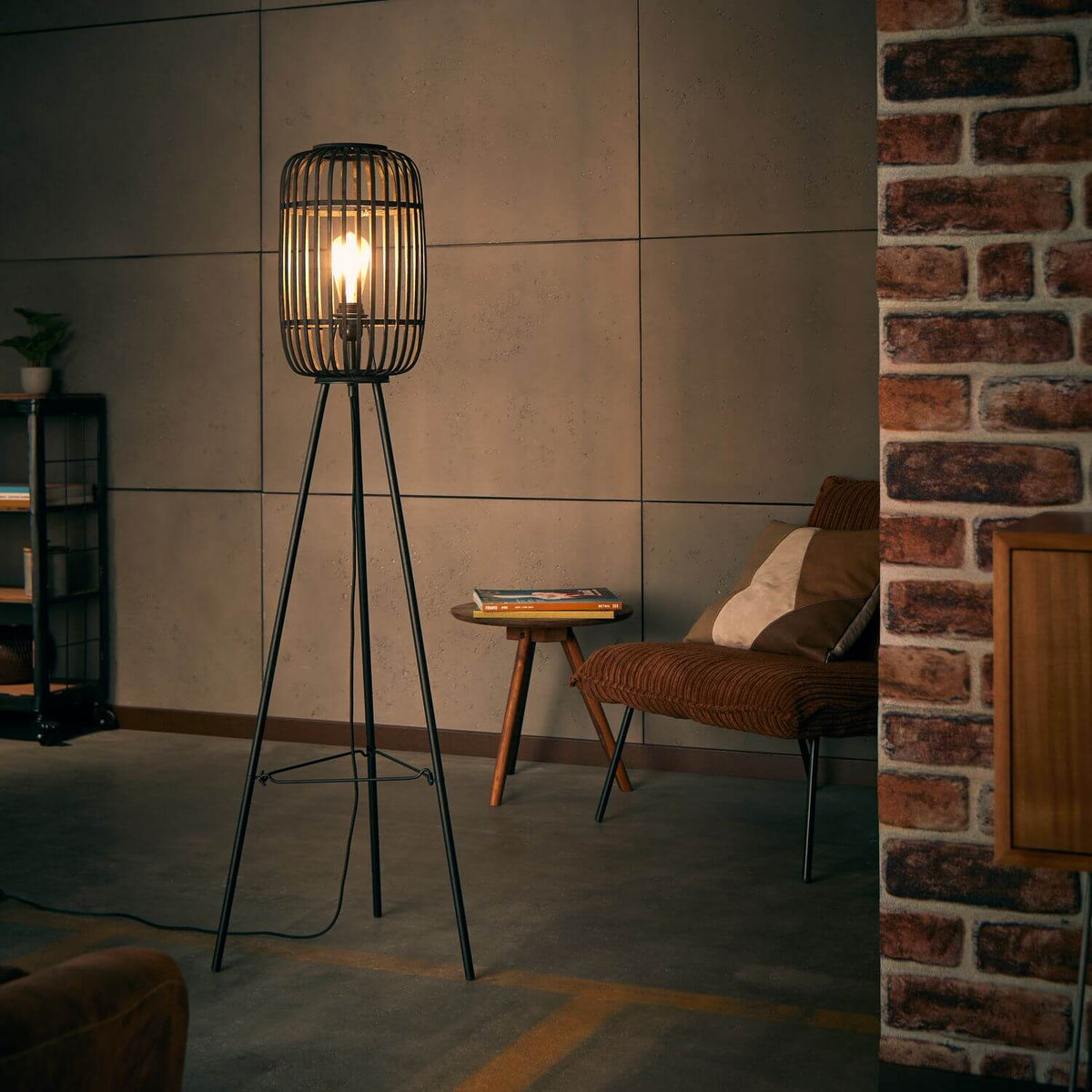 Lampadaire allumé dans un salon, près d'un fauteuil et d'une table basse, mur en briques.