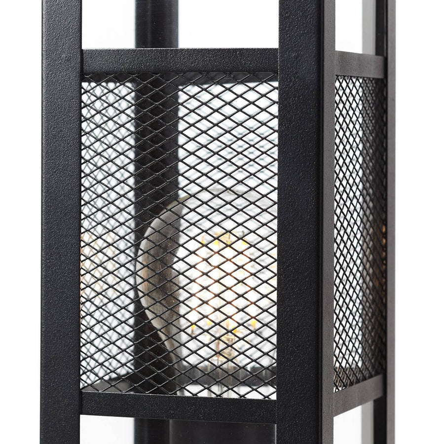 Gros plan sur la grille métallique tressée et l'ampoule chaude du luminaire.