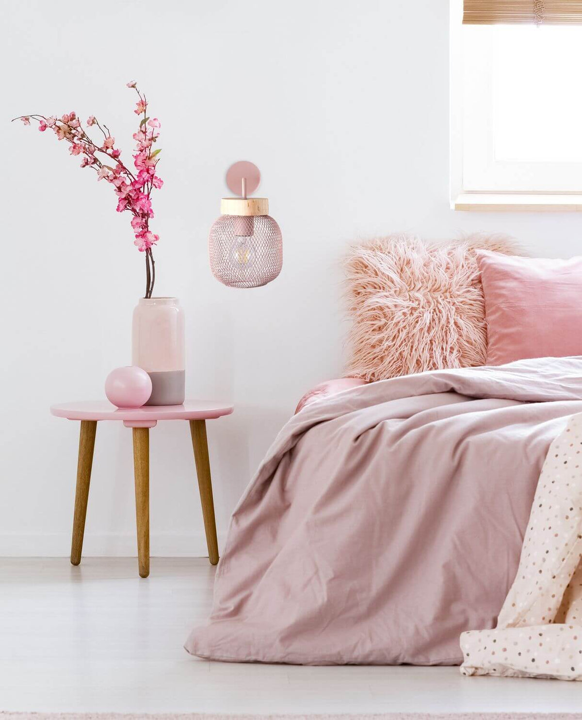 Applique allumée au-dessus d'une table de chevet rose, chambre douce et fleurs de cerisier.