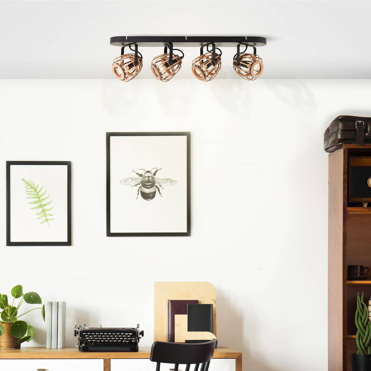 Mise en ambiance dans un bureau, plafonnier allumé au-dessus d'un meuble et d'affiches
