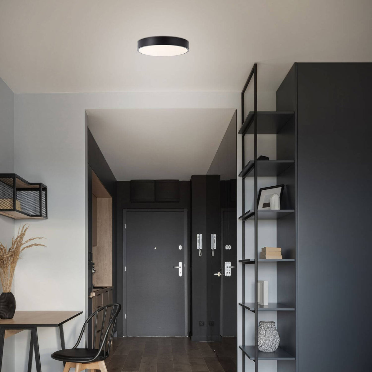 Mise en ambiance dans une entrée moderne avec meuble noir et table en bois