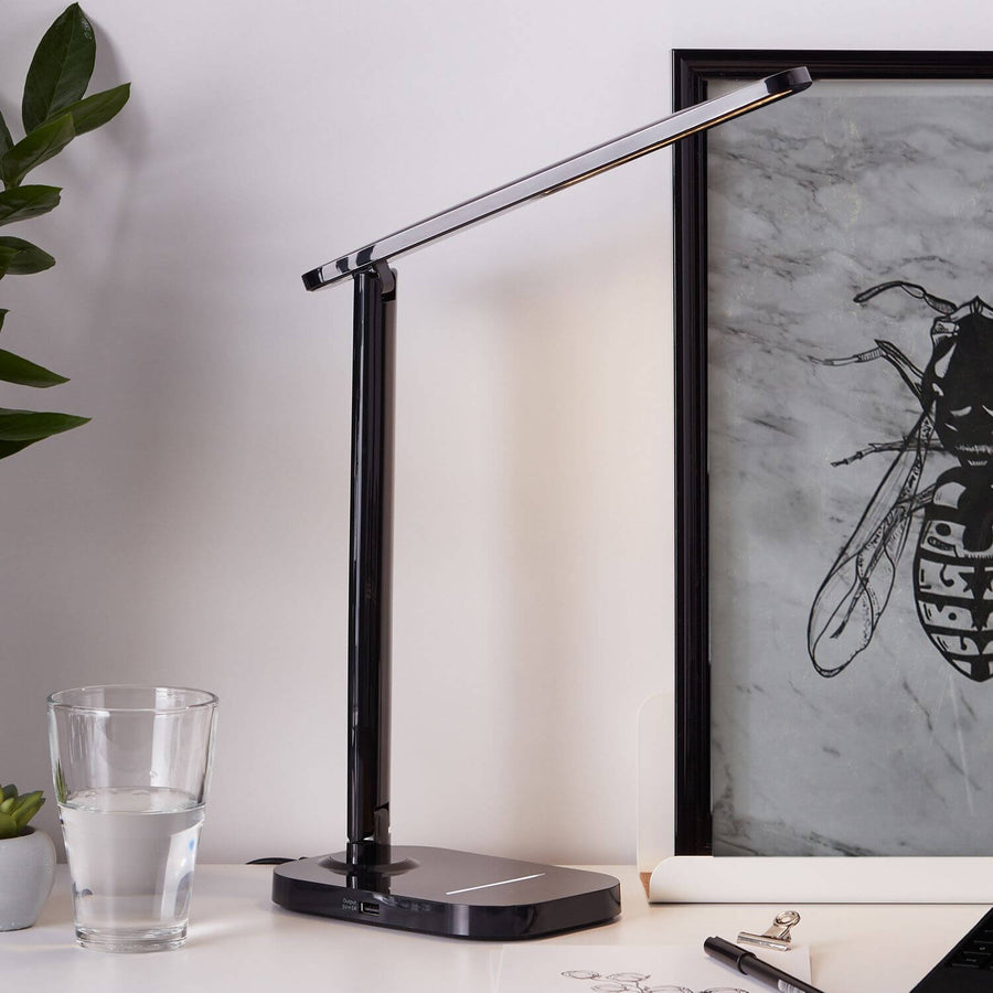 Lampe posée sur un bureau blanc près d'un verre d'eau et d'une plante grasse.