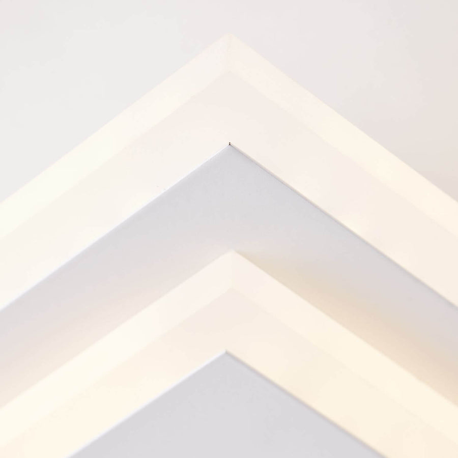 Détail serré de l'angle du cadre blanc et de la lumière LED allumée.