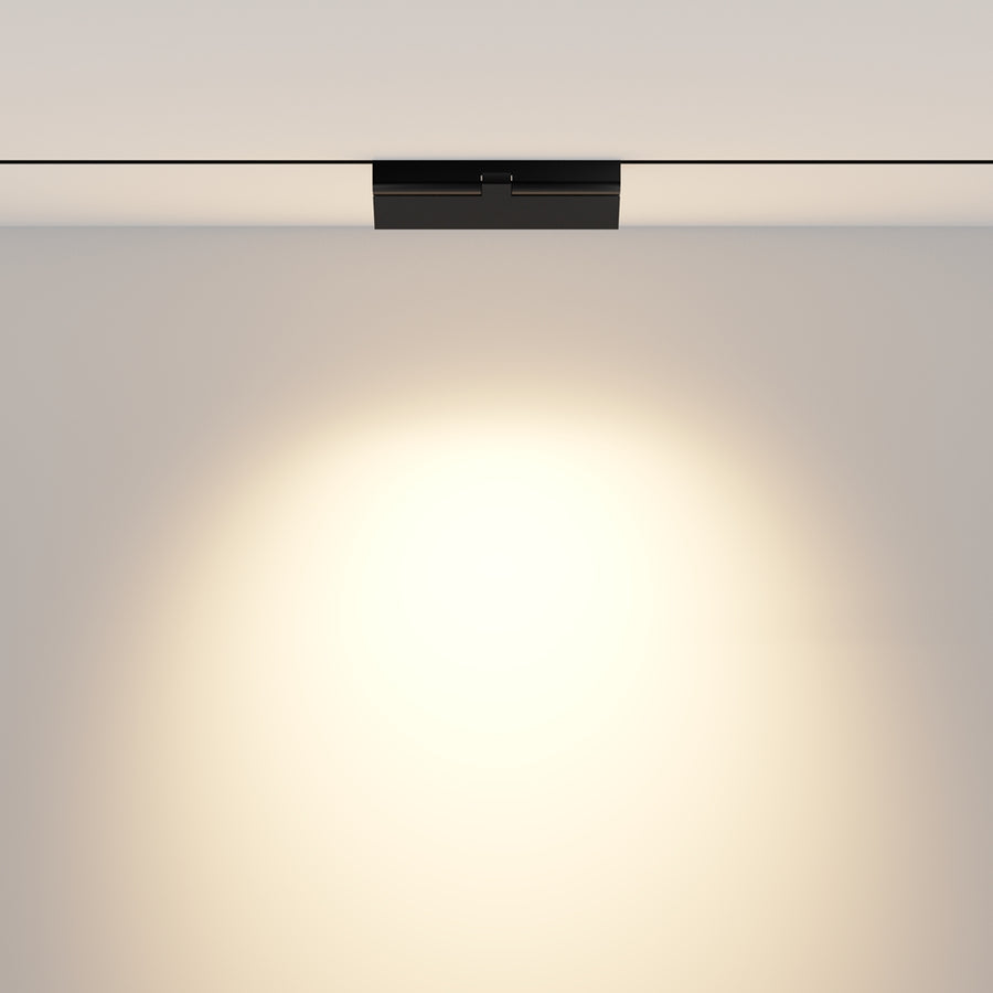 Vue frontale du spot fixé au plafond projetant un halo lumineux sur le mur