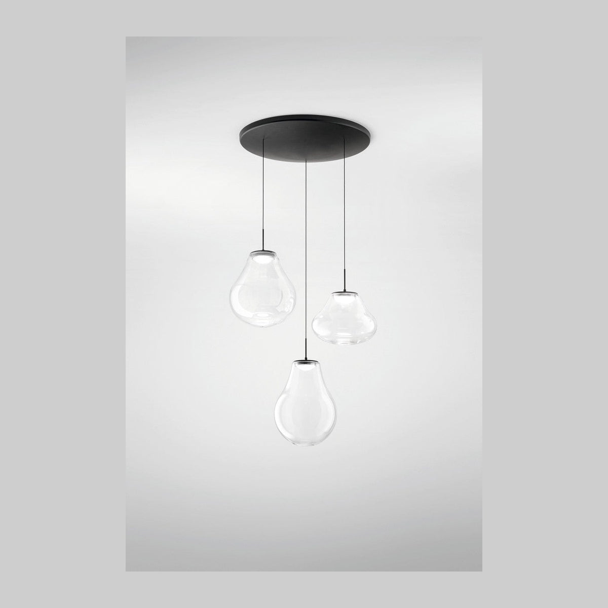 Suspension à trois verres transparents en forme de goutte sous une platine ronde noire
