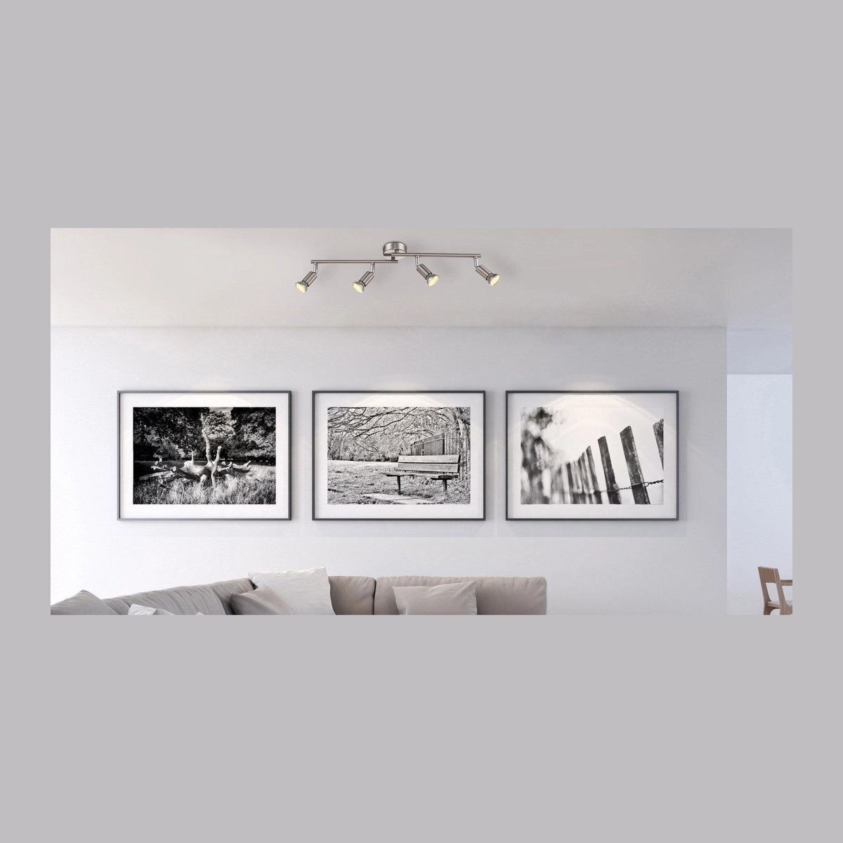 Luminaire fixé au plafond au-dessus d'un canapé et de trois cadres noirs et blancs.