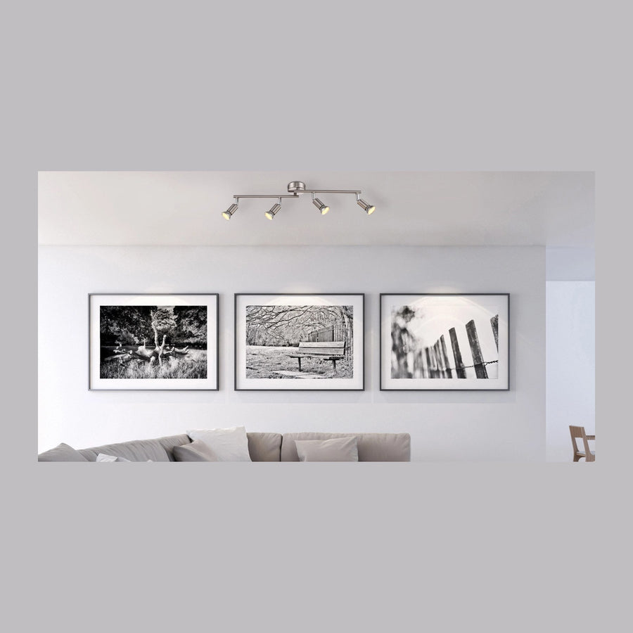 Luminaire fixé au plafond au-dessus d'un canapé et de trois cadres noirs et blancs.
