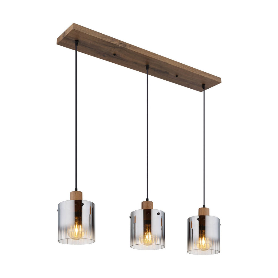 Suspension trois abat-jours cylindriques en verre clair et ampoules filament allumées sur structure bois.
