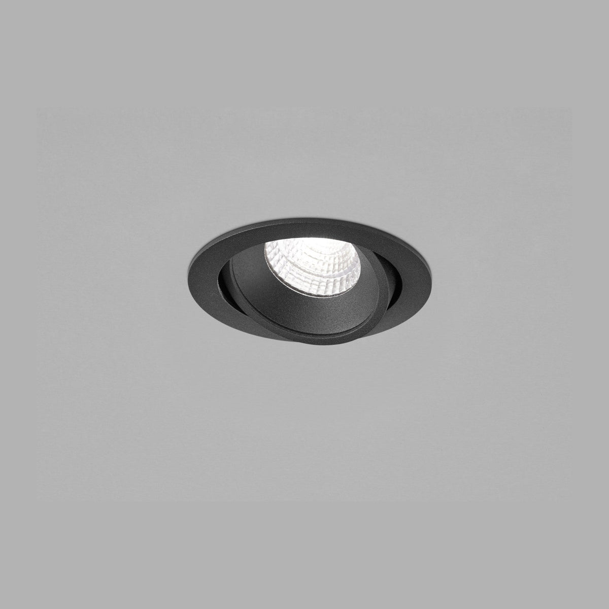 Spot encastré noir vu de face, cercle orientable et lentille striée allumée