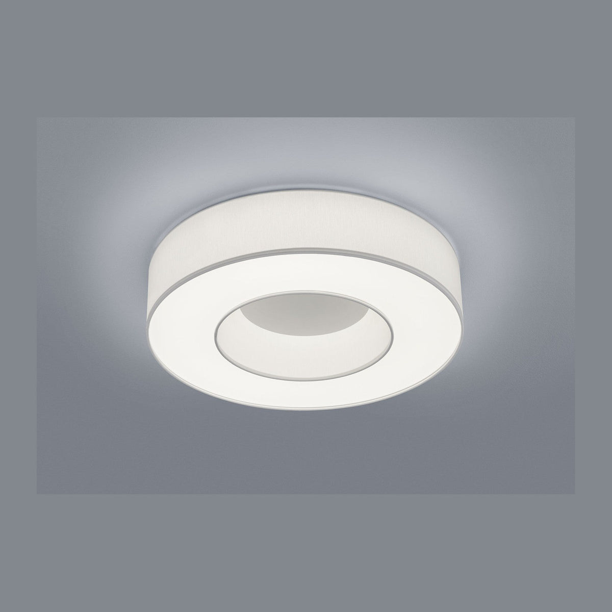 Plafonnier rond blanc vu de dessous sur fond gris, partie centrale en retrait.