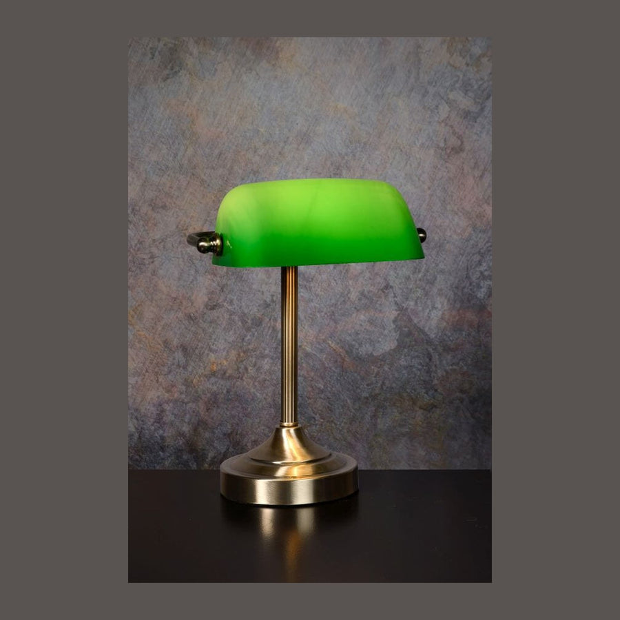 Lampe de bureau verte et laiton, vue de face sur fond gris moucheté.
