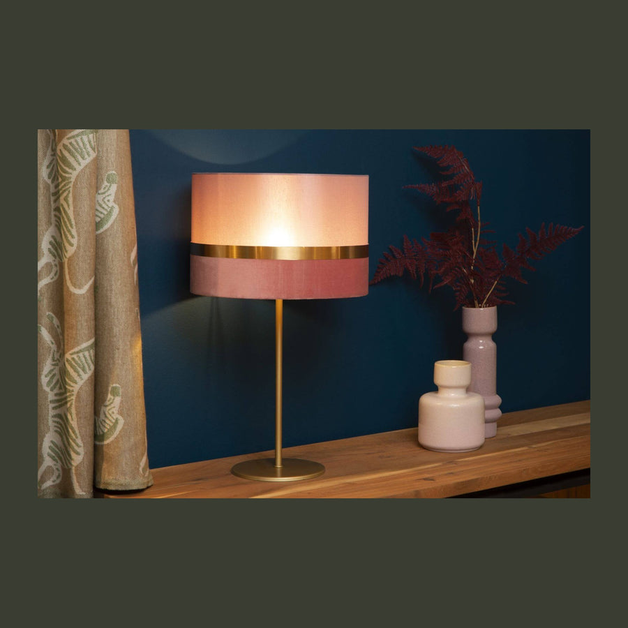 Lampe posée sur buffet en bois devant un mur bleu nuit, décor de vases roses