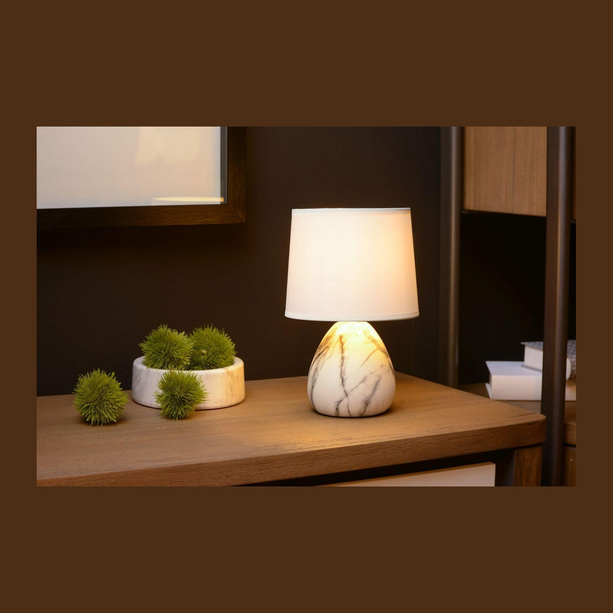 Lampe à poser allumée sur un meuble en bois, décor sombre et plantes vertes