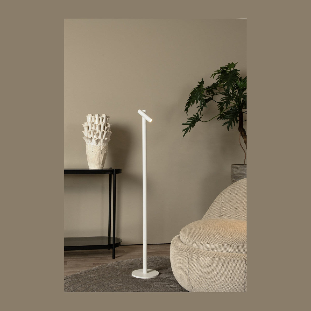 Lampadaire extérieur blanc placé dans un salon près d'un canapé et d'une plante.